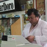 Immagine di un tabaccaio che mostra gratta e vinci con un sorriso, circondato da biglietti vincenti.