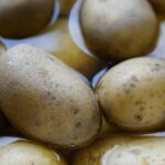 Patate immerse in acqua fredda pronte per essere cotte su un fornello acceso.