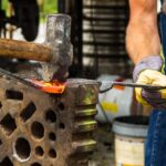 Operaio metalmeccanico al lavoro in un'officina, circondato da attrezzature e macchinari.